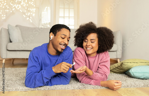 Black young couple handing over earbud to listen music indoor