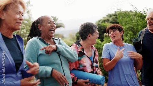 Happy sports group of senior people having fun after exercising outdoors in nature. Multiracial elderly community concept