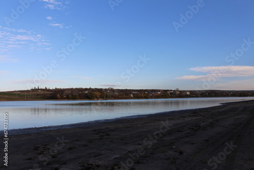 A beach with a body of water and trees in the background