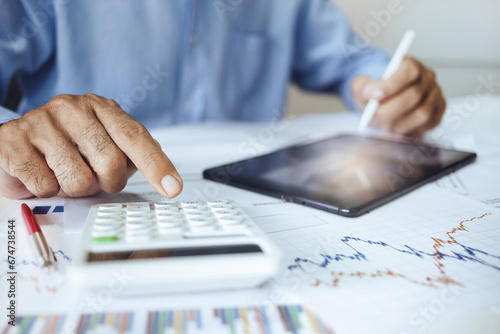 Asian businessman calculate return on investment and using tablet computer to analysis and plan for a future investment, close-up view photo