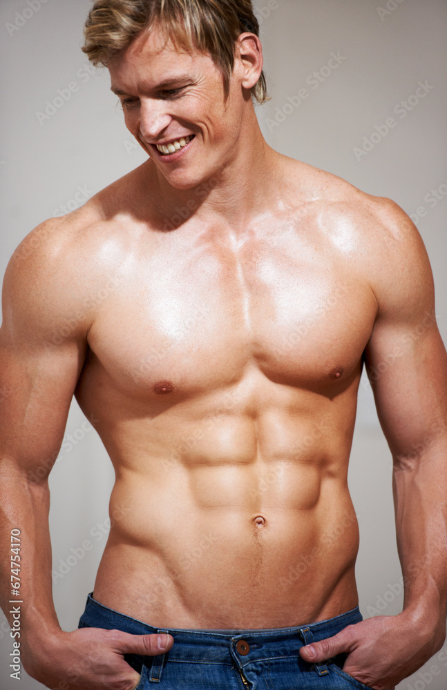 Obraz premium Bodybuilder, man and six pack with sexy smile, topless and body with muscle, strong and model in studio background. Confident, workout and fitness with stomach, chest for health, exercise and abs