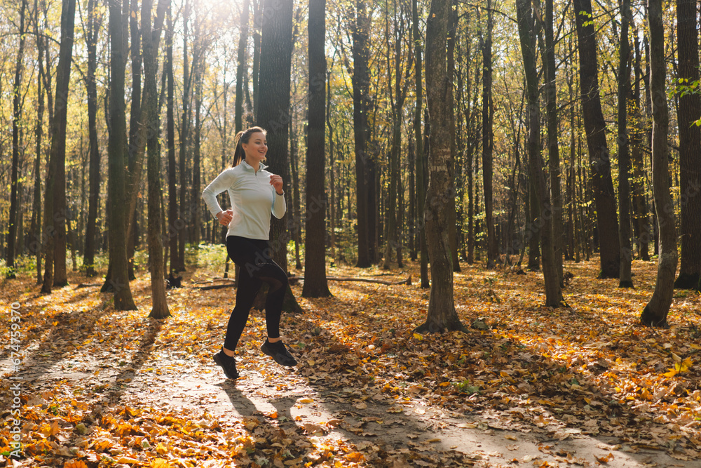 Fototapeta premium Beautiful girl doing fitness in nature on a sunny autumn forest. Body positive, sports for women, harmony, healthy lifestyle, self-love and wellness.
