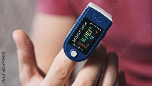 Pulse oximeter measures pulse and oxygen saturation on a male finger close-up. Modern device measure heart rate pulse and heartbeat health at home. Monitoring blood status. Health, medical technology photo