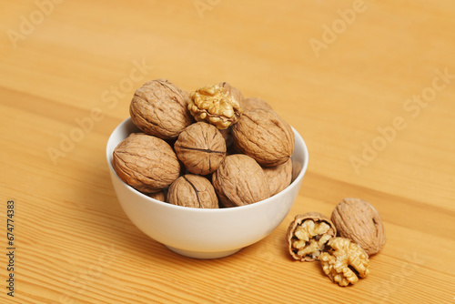 white bbowl of walnuts on wooden surface