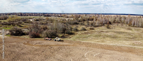 Agricultural machinery in a field near a small grove, aerial view. Agricultural land.