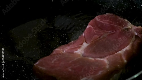 Chef puts pork steak in a frying pan. Cooking raw meat. Preparetion food for dinner photo