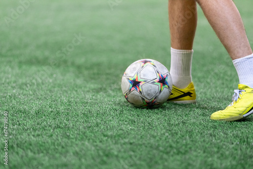 Fototapeta Naklejka Na Ścianę i Meble -  Football Futsal ball and man player legs on artificial grass field indoors.