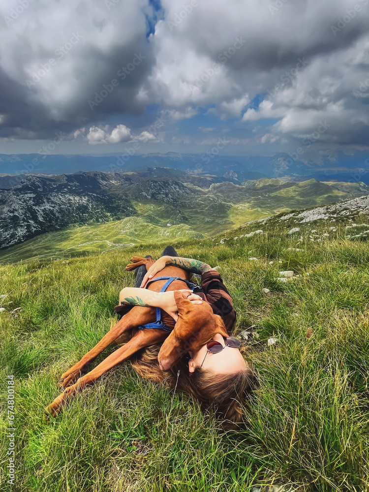 Woman with Vizsla Dog Lying on Mountain Top