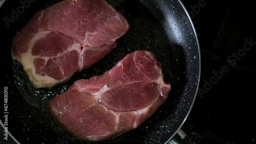 Cooking pork steak in a frying pan. Top view. Preparetion food for dinner photo