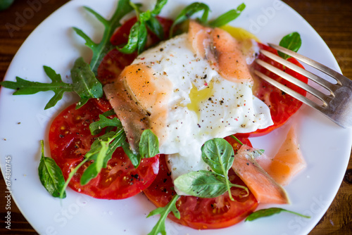 Cooked poached egg with herbs, lightly salted salmon and tomatoes with spices .