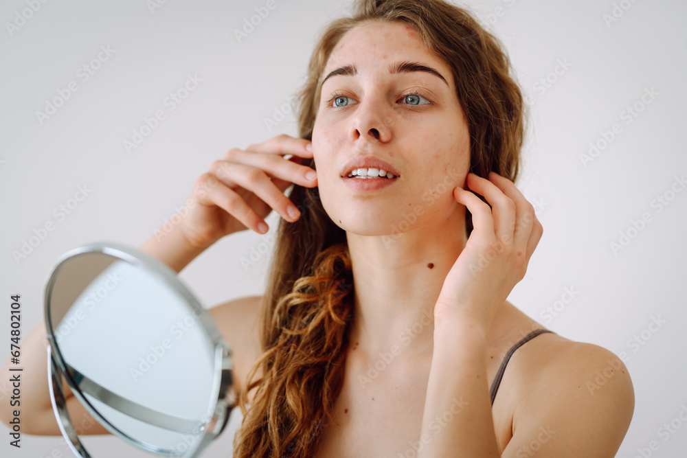 Dermatology. A beautiful woman looking in the mirror, touching her face with her hand, examines acne, pigmentation. Cosmetic care. Allergic reaction. Health concept, cosmetology. Dermatology. A beautiful woman looking in the mirror, touching her face with her hand, examines acne, pigmentation. Cosmetic care. Allergic reaction. Health concept, cosmetology.