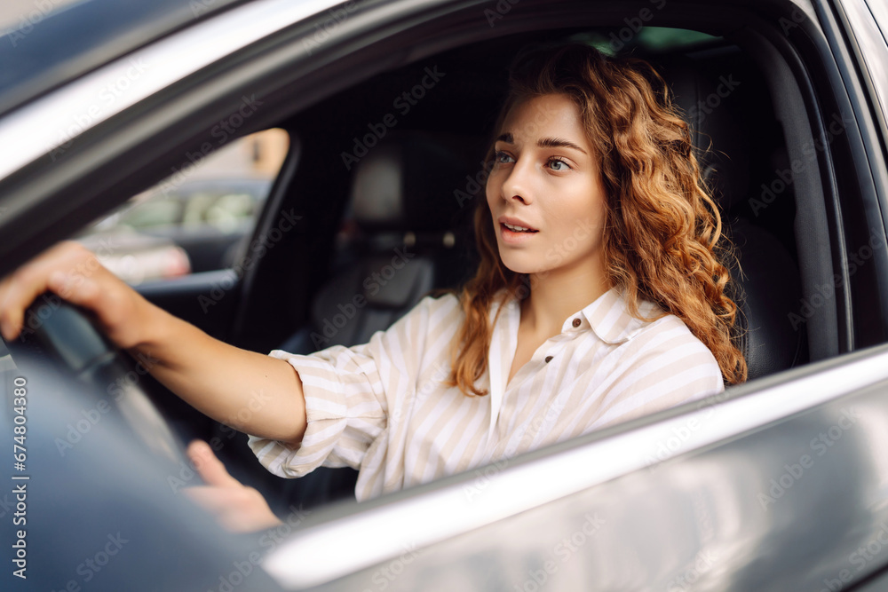 Smiling woman driving her car. Portrait of a stylish woman in casual clothes driving a car. Car travel concept.