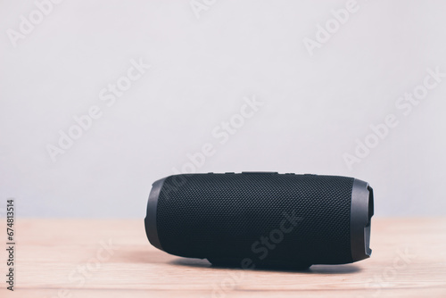 Portable loudspeaker on the table. Music audio column. On a wooden background.