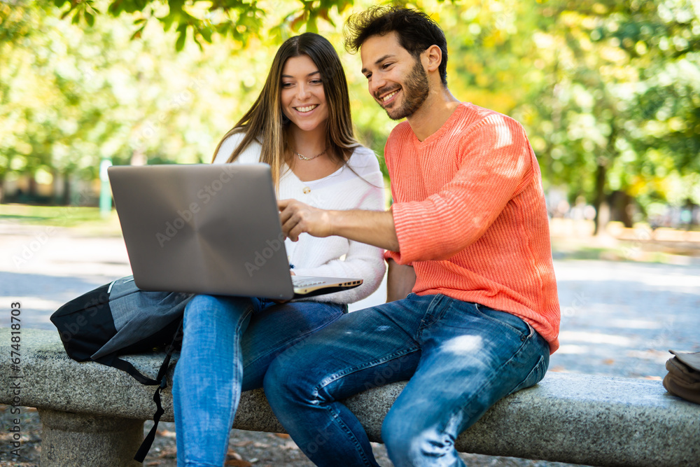 Two students studying together sitting on a bench outdoor Two students studying together sitting on a bench outdoor