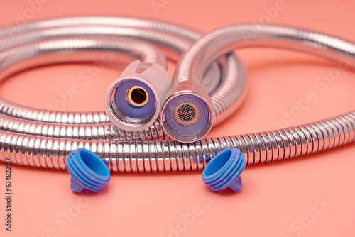 Metal shower hose with plugs on pink background