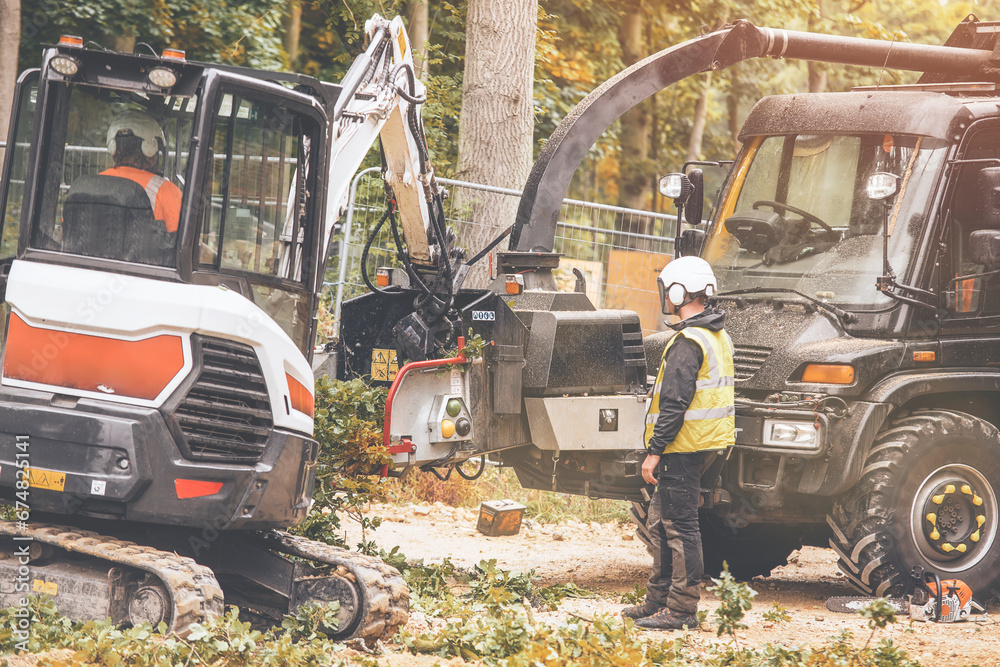 Arborist using a wood chipper machine for shredding trees and branches. The tree surgeon is