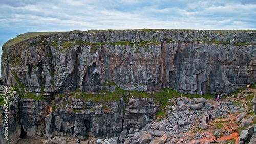 Tourists visit the historical landmark of Saint Govan's Chapel. View of a tiny cliffside chapel accessed by steps at Pembrokeshire Coast National Park in Wales. photo