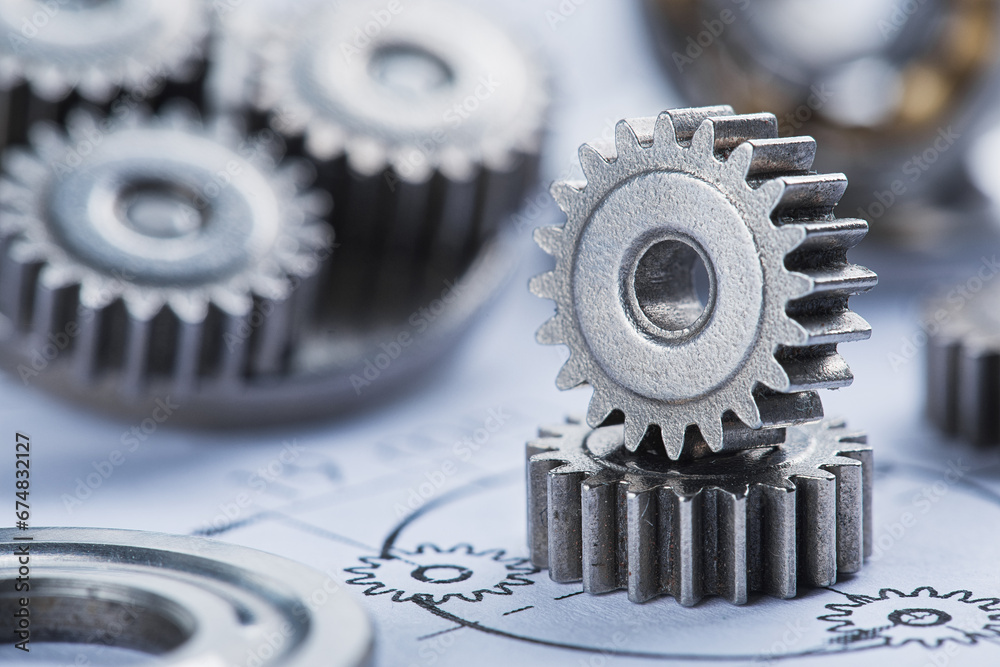 Close up metal gears and bearings. Background with drawings of the mechanism. Industrial mechanism. Close up metal gears and bearings. Background with drawings of the mechanism. Industrial mechanism.