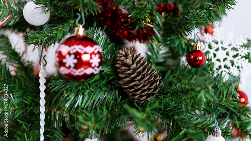 Christmas tree branches decorated with a Xmas balls and a pine cone.