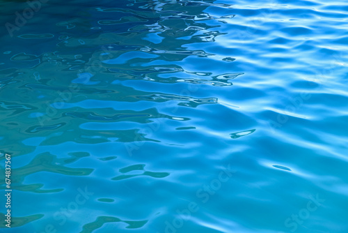 Blue water with ripples on the surface. Defocused blurred colorful transparent water surface texture. Abstract surface. Water waves with shining pattern texture background.