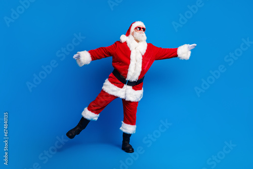 Full length photo of mature pensioner man dance look empty space dressed stylish santa claus costume coat isolated on blue color background