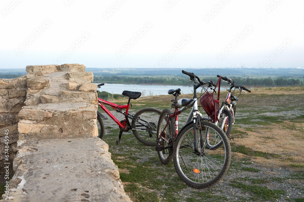 Fototapeta premium Panoramic evening view of the reservoir from the high river bank with ancient ruins. At the historic ruins are a few bicycles.