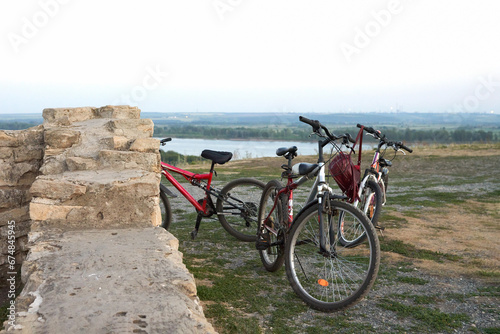 Fototapeta Naklejka Na Ścianę i Meble -  Panoramic evening view of the reservoir from the high river bank with ancient ruins. At the historic ruins are  a few bicycles.