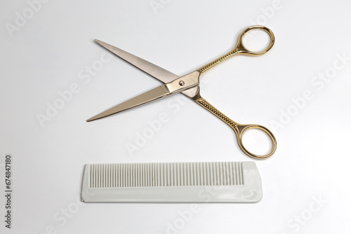 Golden scissors and plastic comb on a white background. Beauty, fashion, haircut, style concept.
