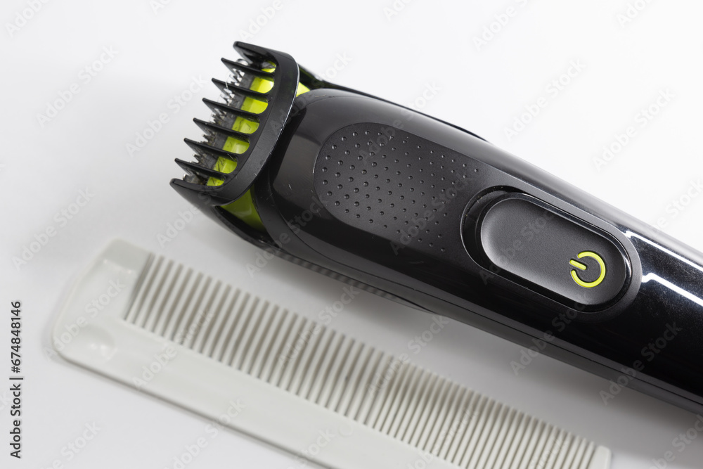 Electric shaver and plastic comb used for shaving hair, beard and moustache on a white background. Multi-purpose rechargeable shaver. Electric shaver and plastic comb used for shaving hair, beard and moustache on a white background. Multi-purpose rechargeable shaver.