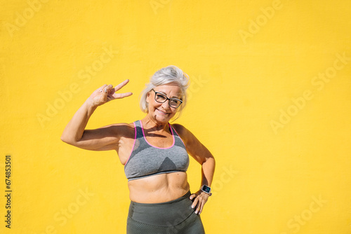 Elder sportive woman gesturing victory with hands photo