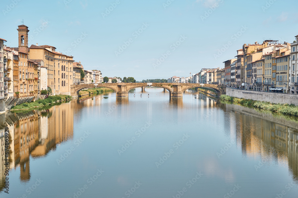 Santa Trinità bridge, seen from Ponte Vecchio, on a summer day with blue sky and reflections on the Arno