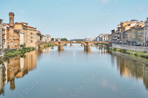 Santa Trinità bridge, seen from Ponte Vecchio, on a summer day with blue sky and reflections on the Arno