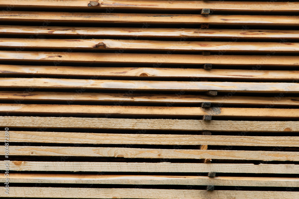 many stacked brown boards. structural light wooden background. the concept of working at a sawmill many stacked brown boards. structural light wooden background. the concept of working at a sawmill