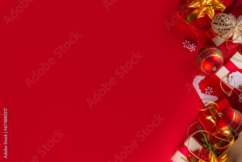 Christmas and New Year sale, shopping background, banner template. Bright red flat lay with paper shopping bag full of gifts, Christmas decorations, fir tree branches, with shopping and sale tags