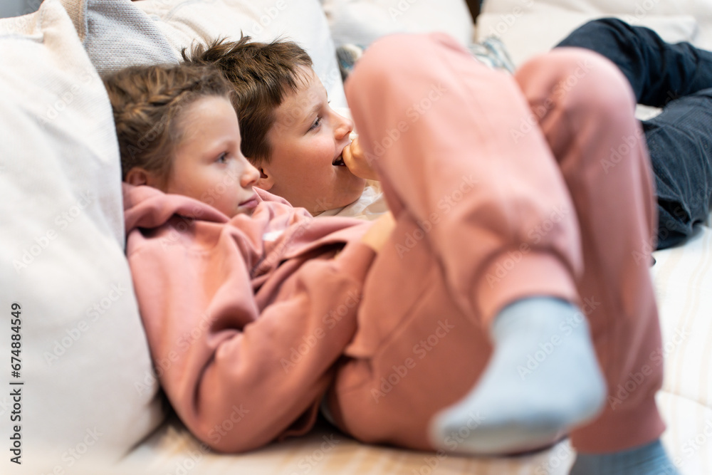 Children watching exciting cartoon and smiling. Common interests among children. Ordinary everyday life of a simple family.
