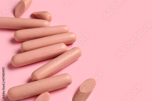 Tasty thin sausages on pink background