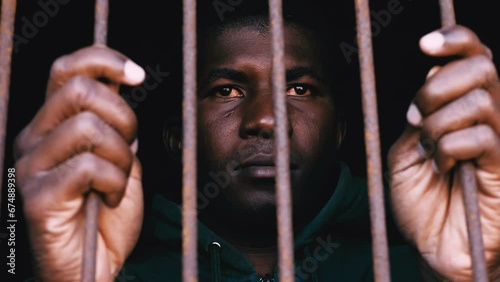 sad young african man behind the bars looks away with thoughtfully look photo