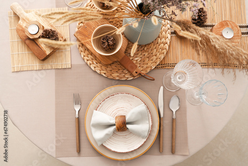 Elegant table setting with cutlery, plates and dried flowers
