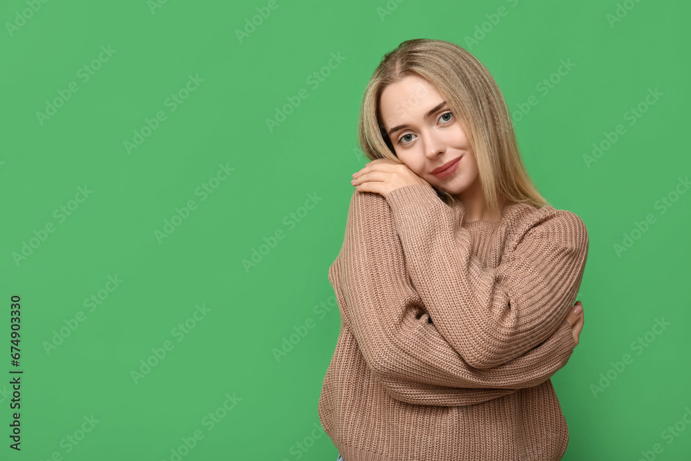 Young woman embracing herself on green background Young woman embracing herself on green background