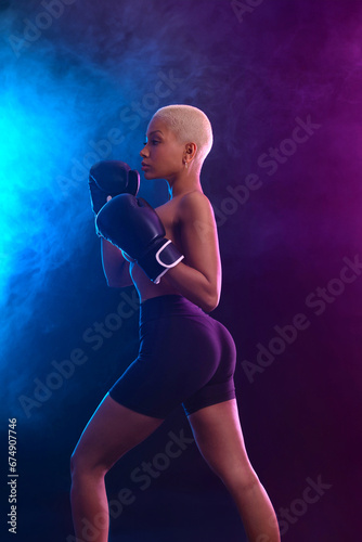 The Boxing. Brazilian woman boxer. Sportsman muay thai boxer fighting in gloves. Isolated on black background. Copy Space. © Mike Orlov