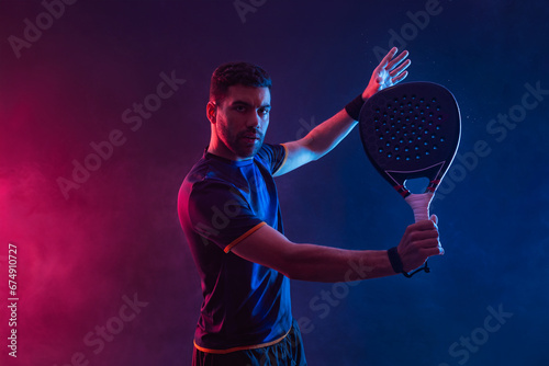 Padel tennis player. Man athlete with paddle tenis racket on neon background. Sport concept. Download a high quality photo for sports website.