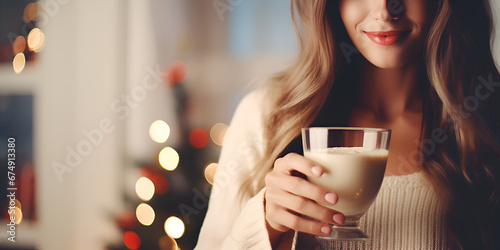 Close up of woman's hands  holding a eggnog drink at Christmas market, blurred background with lights 
