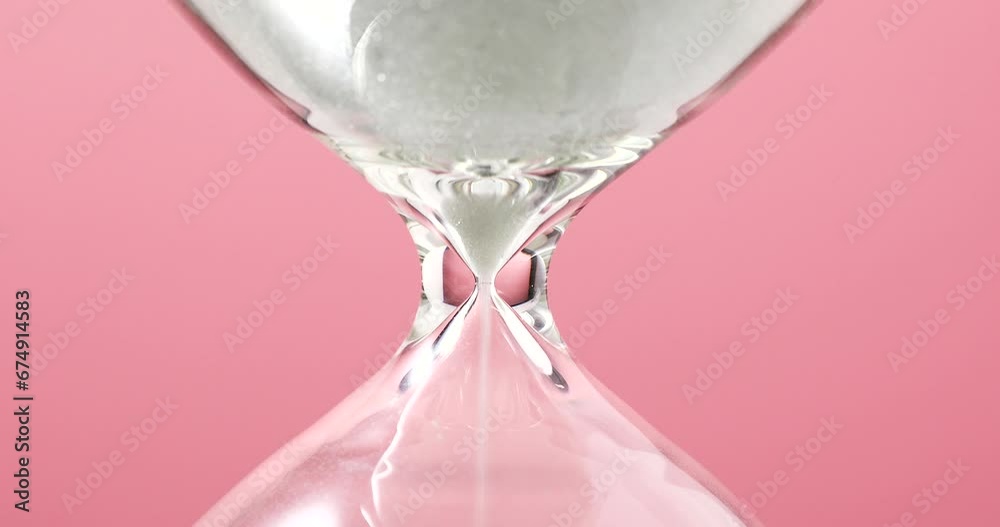 Close-up of an hourglass on a pink background, concept of time passing