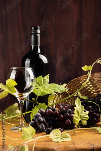 Grapes and wine, basket with beautiful grapes and bottle of red wine, on rustic wood, selective focus.