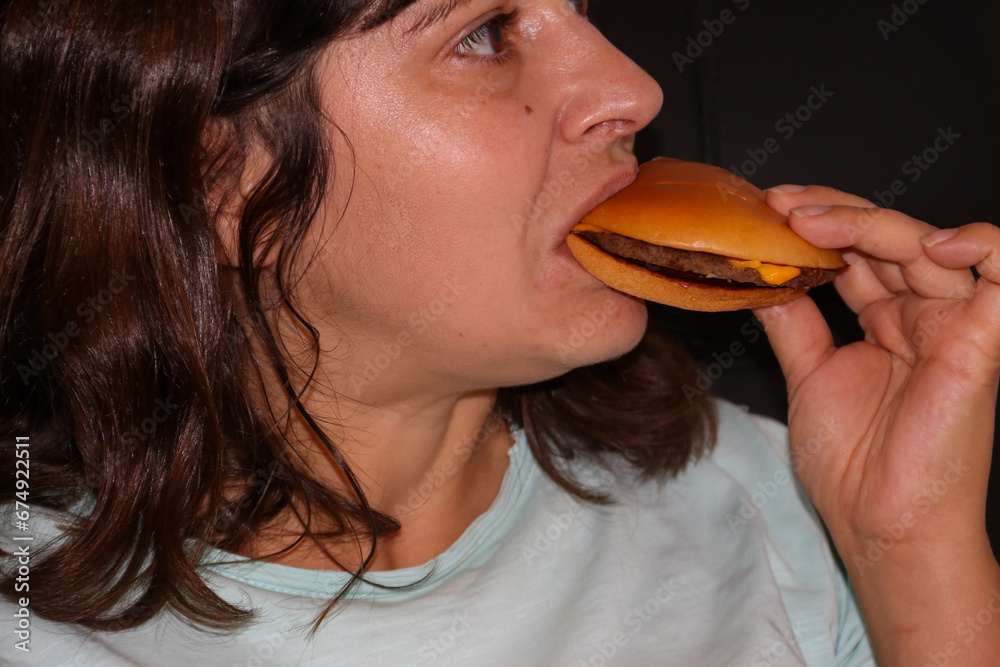 Caucasian woman eating tasty cheeseburger Caucasian woman eating tasty cheeseburger
