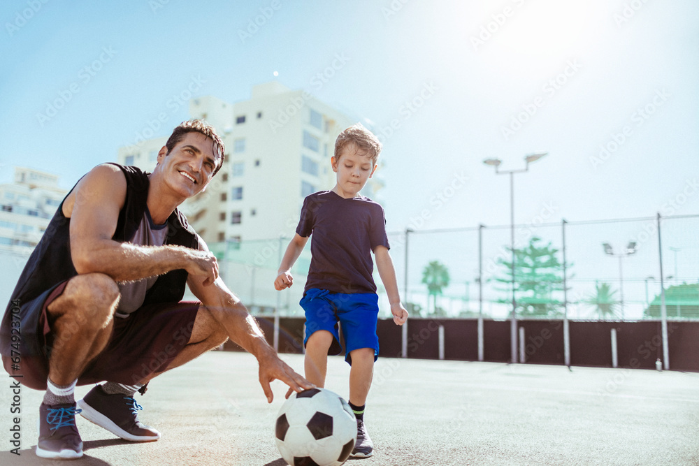 Father teaching son how to play football. Little boy preparing to kick