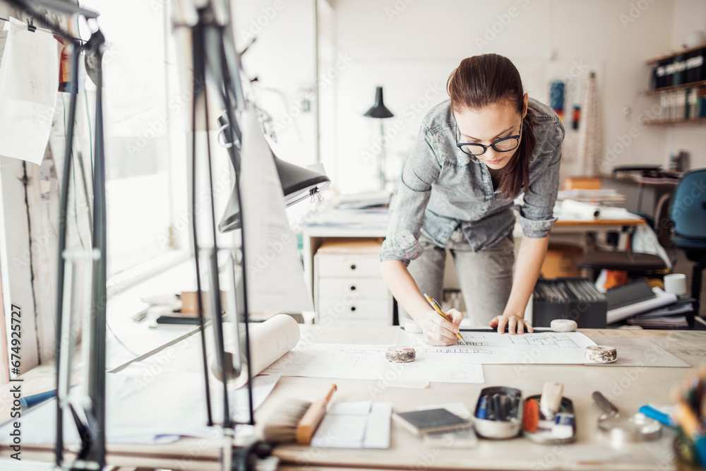 Young female architect sketching a construction project in office Young female architect sketching a construction project in office
