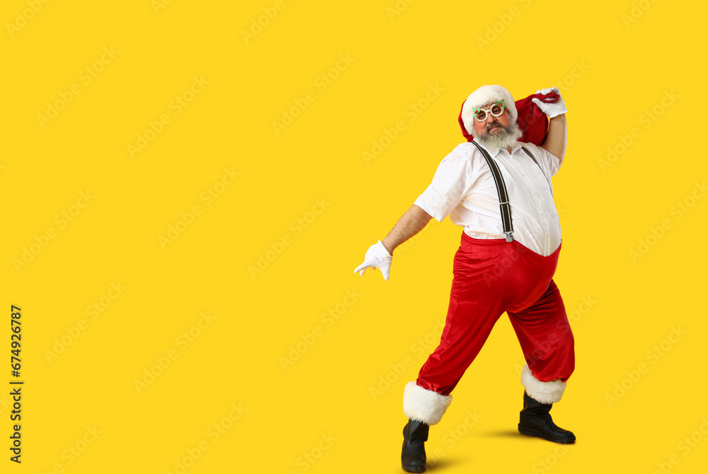 Funny Santa Claus with bag dancing on yellow background Funny Santa Claus with bag dancing on yellow background