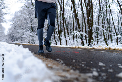 Closeup image of a person walking on wet road, snow on the ground and sports equipment in focus.