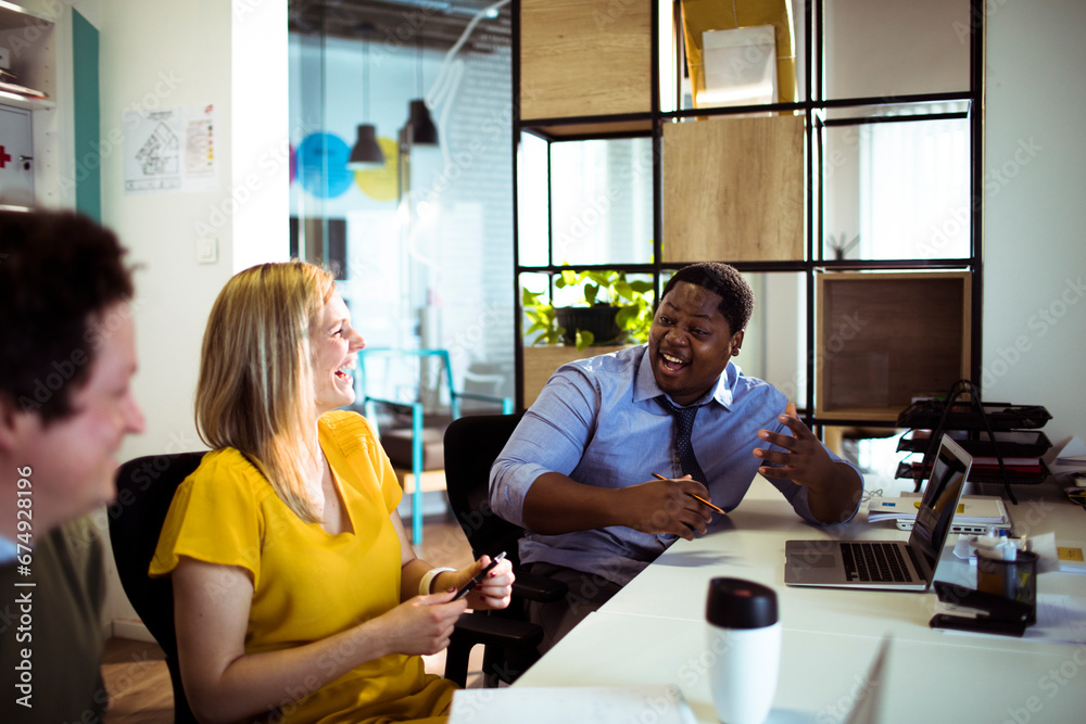 Young colleagues laughing during meeting in modern office Young colleagues laughing during meeting in modern office